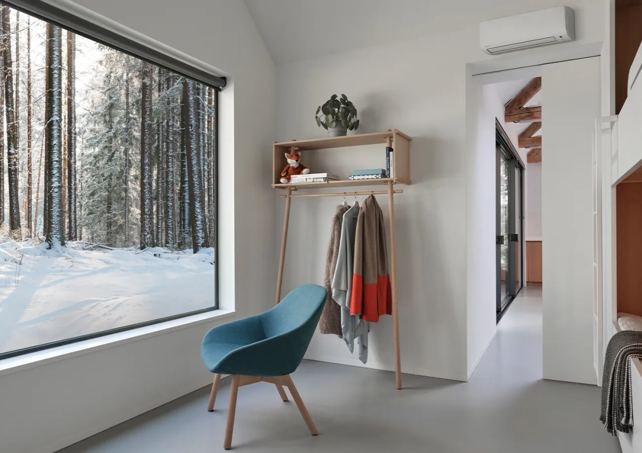 Daikin Comfora på veggen i et lyst hytterom med snø utenfor vinduet