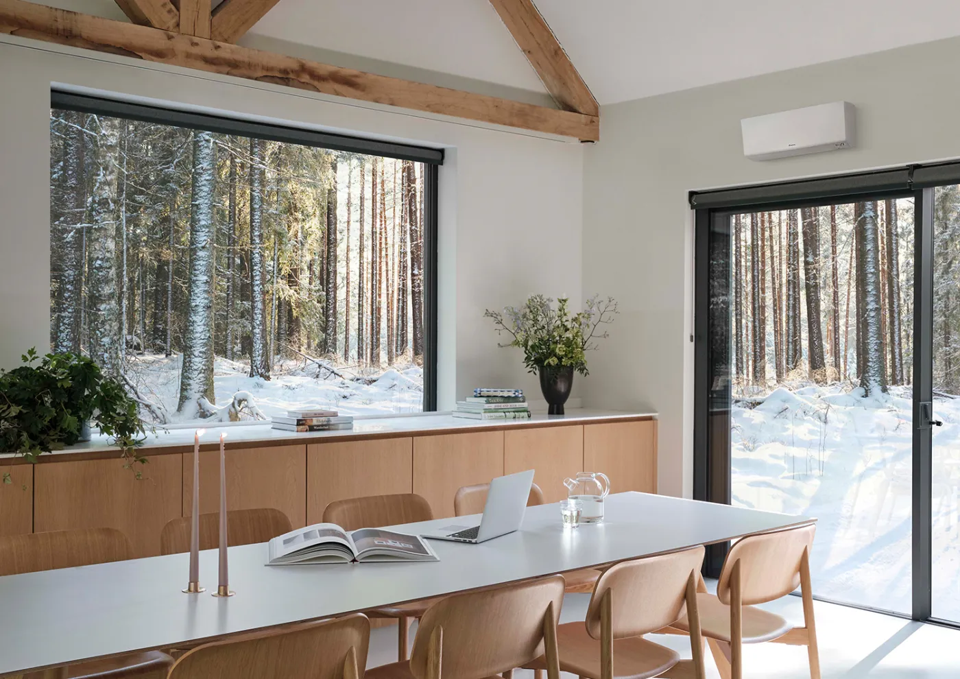Daikin Synergi i et lyst, nordisk hjem med snødekt skog utenfor vinduene