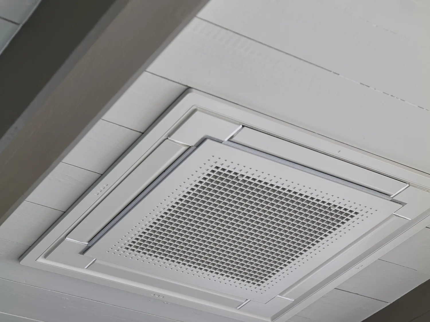 Nærbilde av en Daikin Takkassett innfelt i et malt tretak i en hytte